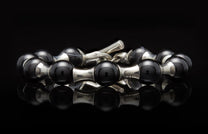 Black onyx and silver beaded bracelet with hourglass links and a cross-engraved toggle clasp.