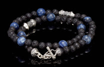 Sodalite tether made of porous black lava stone and marbled blue sodalite beads, featuring intricate silver-toned accent beads and a toggle clasp, displayed on a reflective black surface.