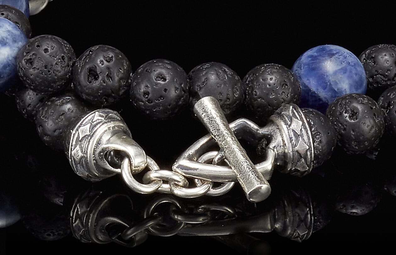 Beaded bracelet with blue sodalite and black lava stone beads, featuring an ornate silver toggle clasp.