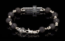 Black lava bead bracelet with silver links, a central hammered silver cross, and an engraved clasp.