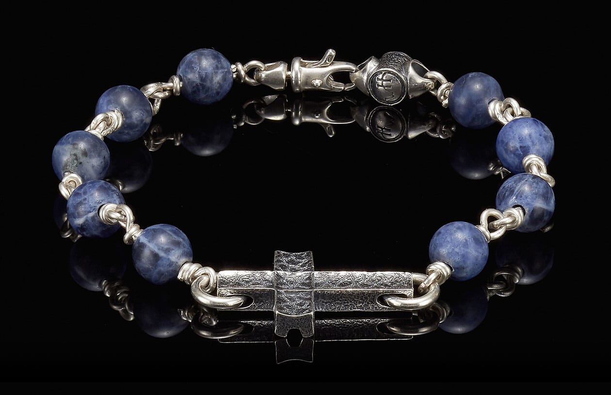 Sodalite beaded bracelet with a textured silver cross, silver links, and a lobster claw clasp.