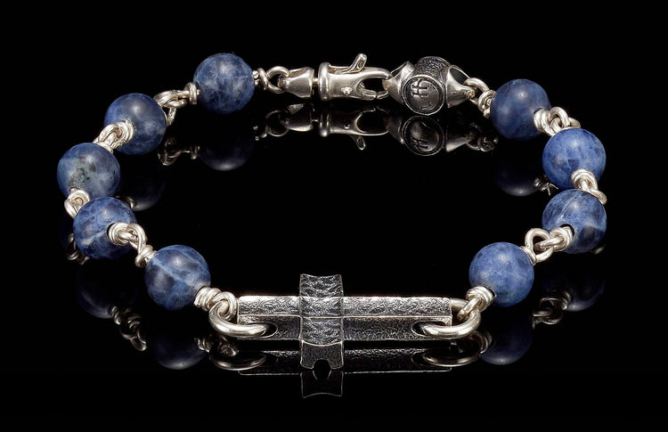 Sodalite beaded bracelet with a textured silver cross, silver links, and a lobster claw clasp.