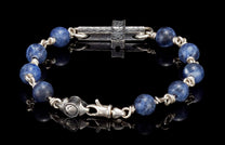 Sodalite beaded bracelet with silver metal wire-wrapped links, a hammered cross centerpiece, and an engraved clasp on a reflective black surface.