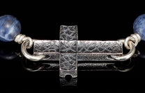 Blue sodalite and silver cross jewelry with an intricately textured cross and connecting rings.