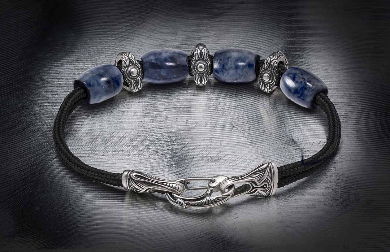Blue sodalite bracelet with black braided cord and ornate silver-toned beads and a decorative hook clasp.
