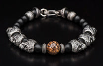 Beaded bracelet with black matte and silver skull beads, featuring a central brown mottled stone and silver clasp.