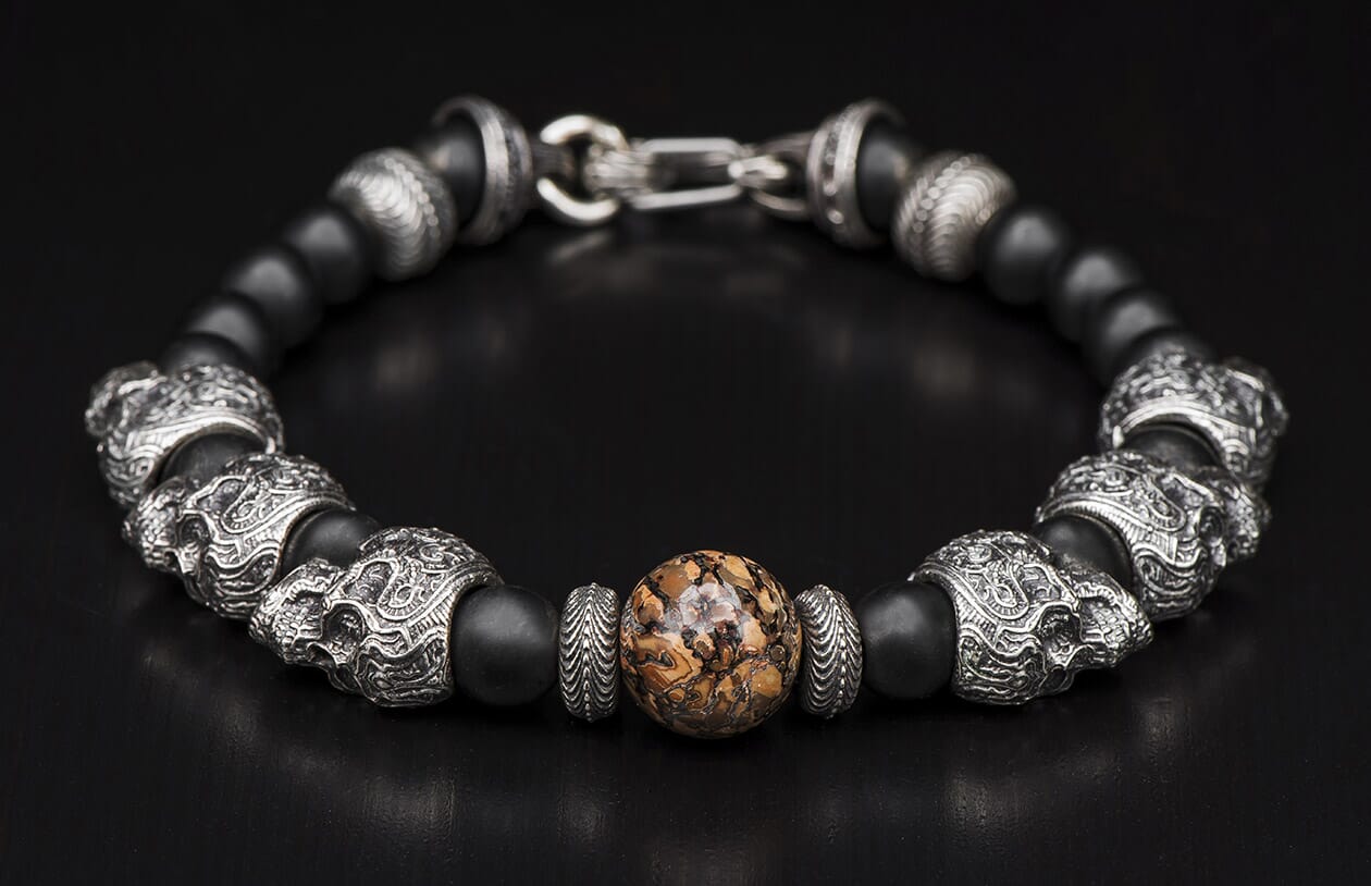 Beaded bracelet with black matte and silver skull beads, featuring a central brown mottled stone and silver clasp.