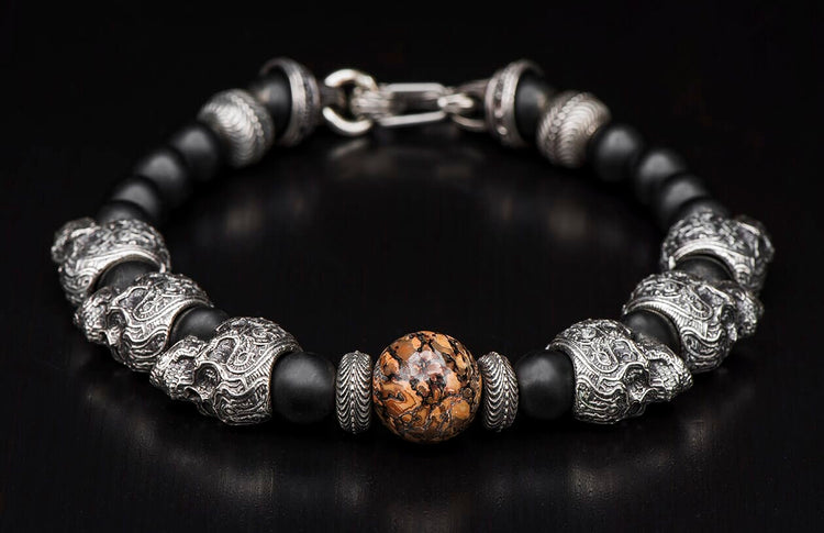 Beaded bracelet with black matte and silver skull beads, featuring a central brown mottled stone and silver clasp.