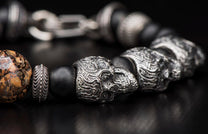 Ornate silver skull and bead bracelet with black matte beads and a brown marbled bead.
