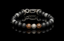 Beaded bracelet with meteorite, dinosaur bone, silver and onyx beads on a dark background