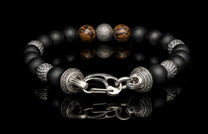 Beaded bracelet with meteorite, dinosaur bone, silver and onyx beads on a dark background
