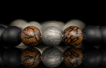 Beaded bracelet with meteorite, dinosaur bone, silver and onyx beads on a dark background