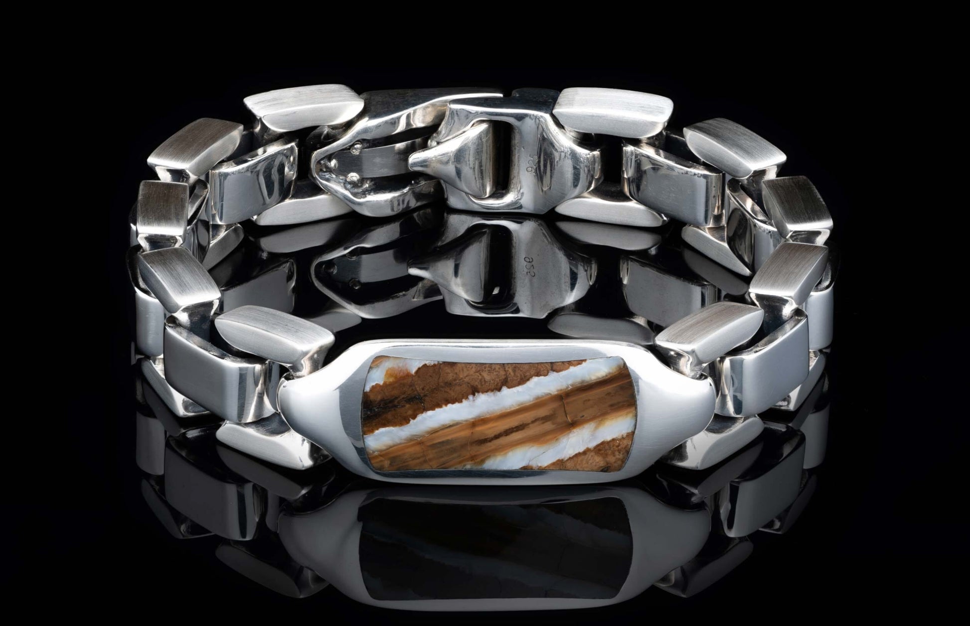 Silver link bracelet with a rectangular inlay of brown and white striped mammoth ivory on a reflective black surface.