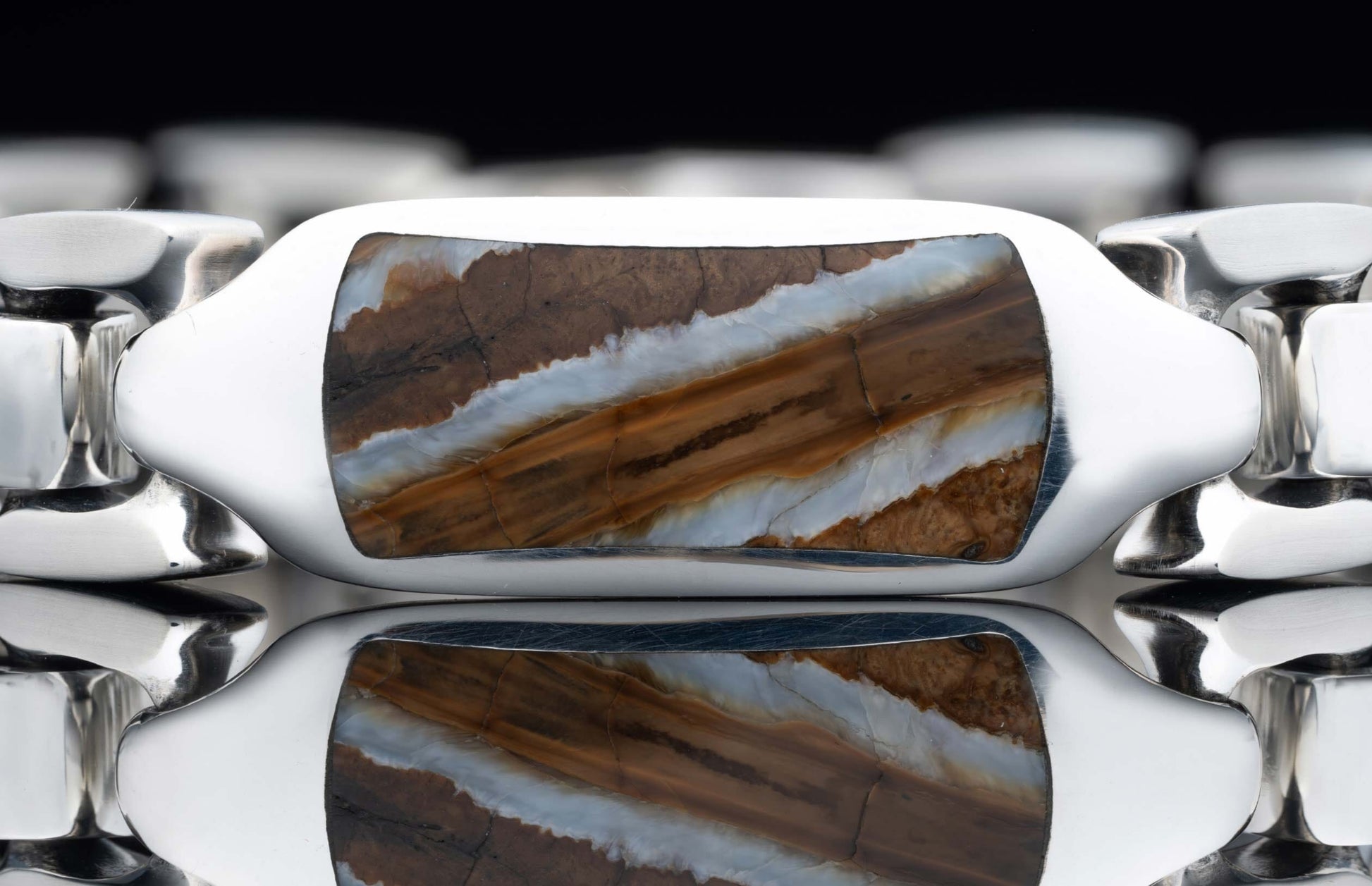 Polished silver bracelet featuring a rectangular stone inlay with wavy brown, white, and orange bands, shown with reflection.