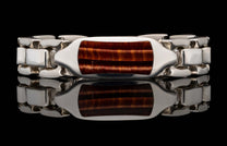 Polished silver identity bracelet with a rectangular red tiger eye gemstone, reflected on a black surface.