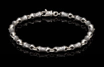 Oxidized silver bracelet with textured, barrel-shaped links and a lobster clasp, reflected on black.