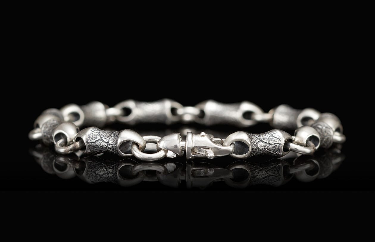 Silver-toned metal bracelet featuring alternating smooth and textured link segments with a distinctive clasp.