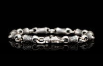 Silver-toned metal bracelet featuring alternating smooth and textured link segments with a distinctive clasp.
