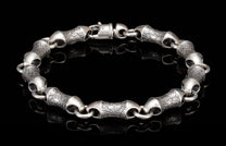 Silver-toned metal bracelet with textured cylindrical links, smooth connecting rings, and a prominent box clasp.