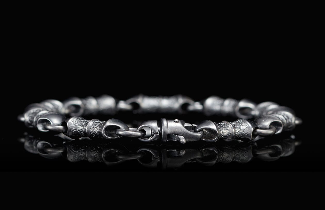 Oxidized silver bracelet with detailed, textured links, a prominent hook clasp, and a clear reflection.