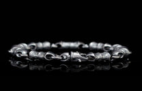 Oxidized silver bracelet with detailed, textured links, a prominent hook clasp, and a clear reflection.