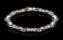 Silver-toned bracelet with alternating textured and smooth cylindrical links, featuring a lobster clasp.