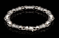 Silver metal bracelet with chunky, textured barrel links featuring an etched pattern and a lobster claw clasp.