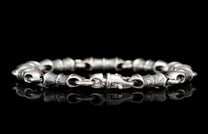 Silver link bracelet with textured and smooth segments, featuring a clasp and reflective surface.
