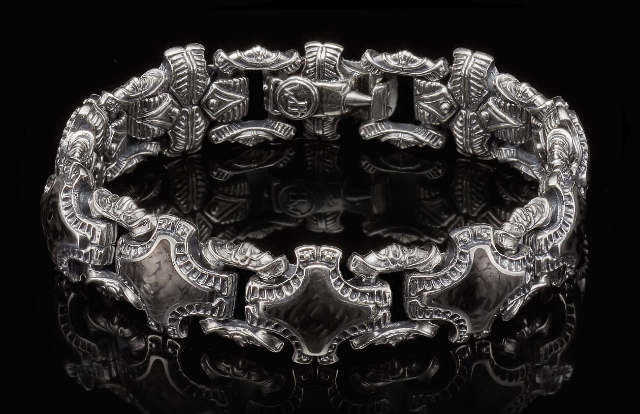 Silver-toned metal "Pawn" bracelet featuring ornate, etched links with scrollwork and a visible clasp with 'KA' emblem.