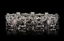 Silver bracelet with ornate, intricate metalwork, textured diamond-shaped links, and a central dark stone detail.