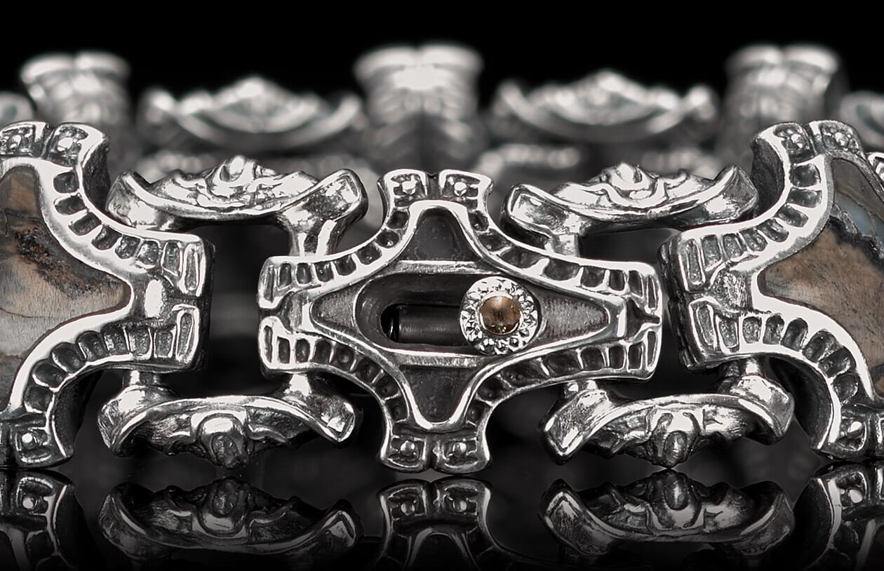 Ornate silver bracelet with intricate links, dark brown inlays, and a central brown gemstone.