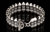 Silver-toned metal bracelet with textured cylindrical beads and black cord, featuring a toggle clasp.