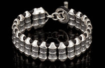 Silver bracelet with textured, ribbed beads on a black cord, featuring a toggle clasp.