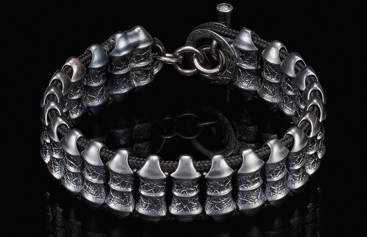 Textured dark silver bracelet with unique tiered metal beads on a black cord and ring clasp.