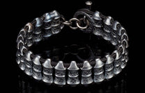 Textured dark silver bracelet with unique tiered metal beads on a black cord and ring clasp.