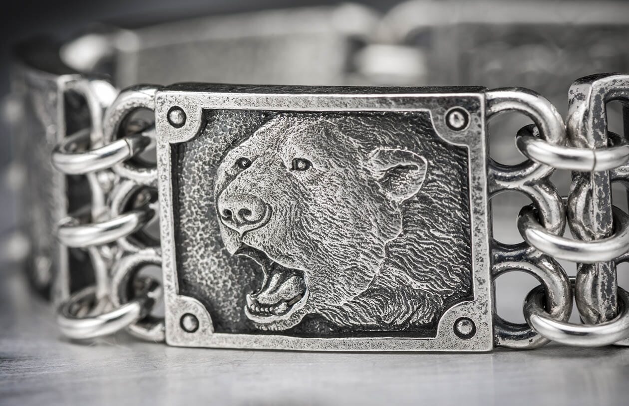 Oxidized silver bracelet featuring a roaring bear's head relief on a central plaque, linked by textured metal chains.