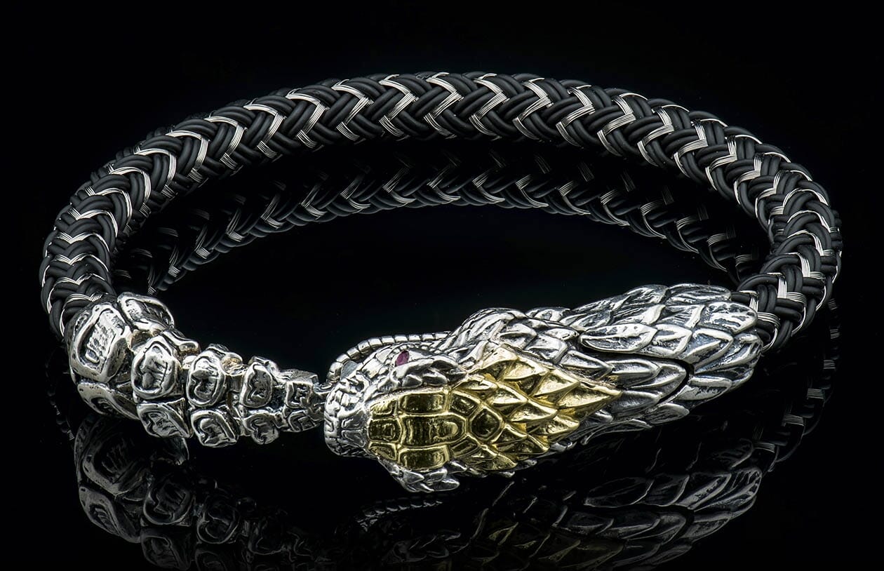 Black and silver braided bracelet featuring a silver snake head with gold accents and a red eye.
