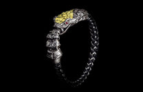Silver snake head bracelet with yellow scales, red eyes, and a braided black and white band.