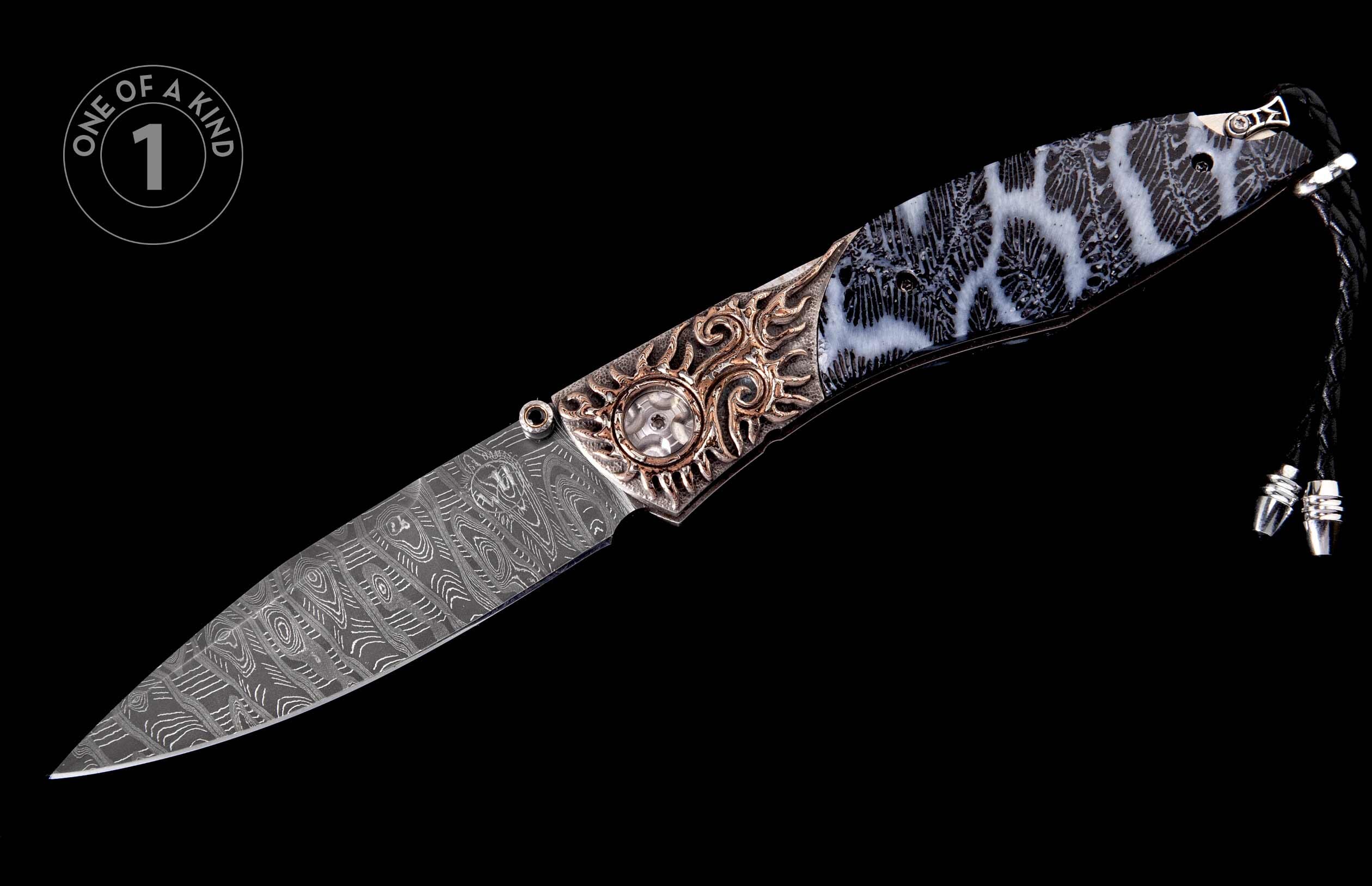 Angled ornate folding knife with a Damascus steel blade, black and white coral-patterned handle scales, and bronze-colored metal embellishments.