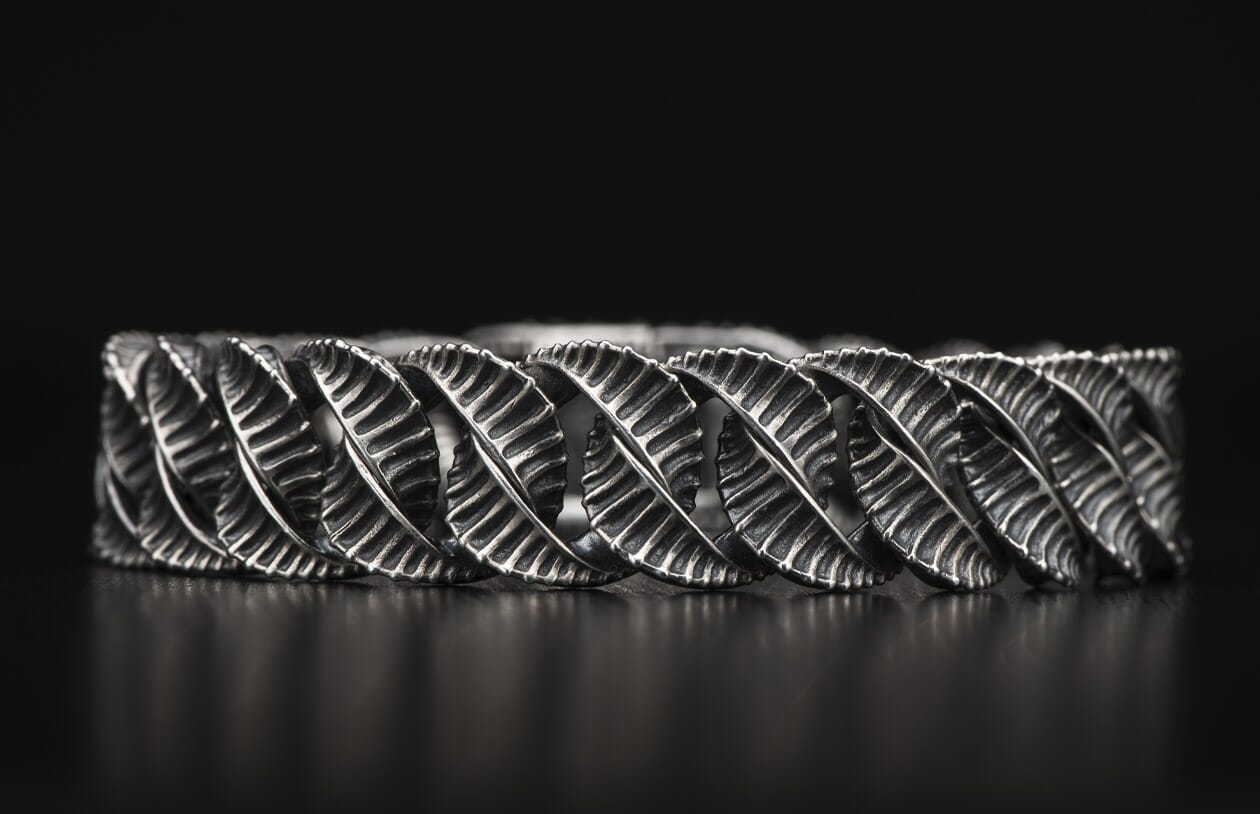 Silver-toned metal bracelet with a twisted, interlocked design of ribbed leaf links and an oxidized finish.