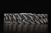 Silver-toned metal bracelet with a twisted, interlocked design of ribbed leaf links and an oxidized finish.
