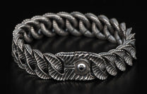 Oxidized silver bracelet featuring intricate leaf-like links and a central black gemstone on the decorative clasp.
