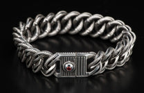 Silver-tone chunky chain bracelet with braided textured links and a decorative clasp featuring a red gemstone.