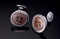 Silver-toned cufflinks with a radial mokume pattern in black and copper, featuring textured rope-like edges.