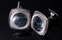 Silver-toned cufflinks with teal and black coral-patterned stones, featuring wavy, ridged frames.