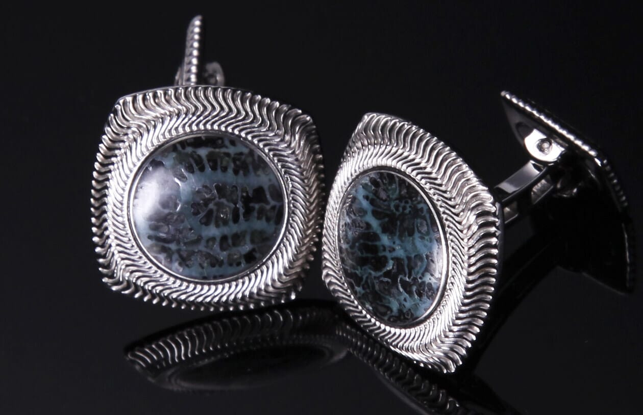 Silver-toned cufflinks with teal and black coral-patterned stones, featuring wavy, ridged frames.