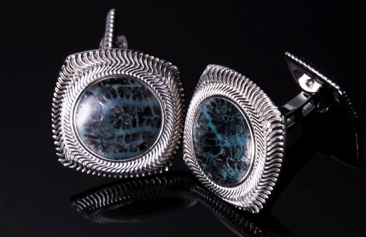 Silver-toned cufflinks with teal and black coral-patterned stones, featuring wavy, ridged frames.