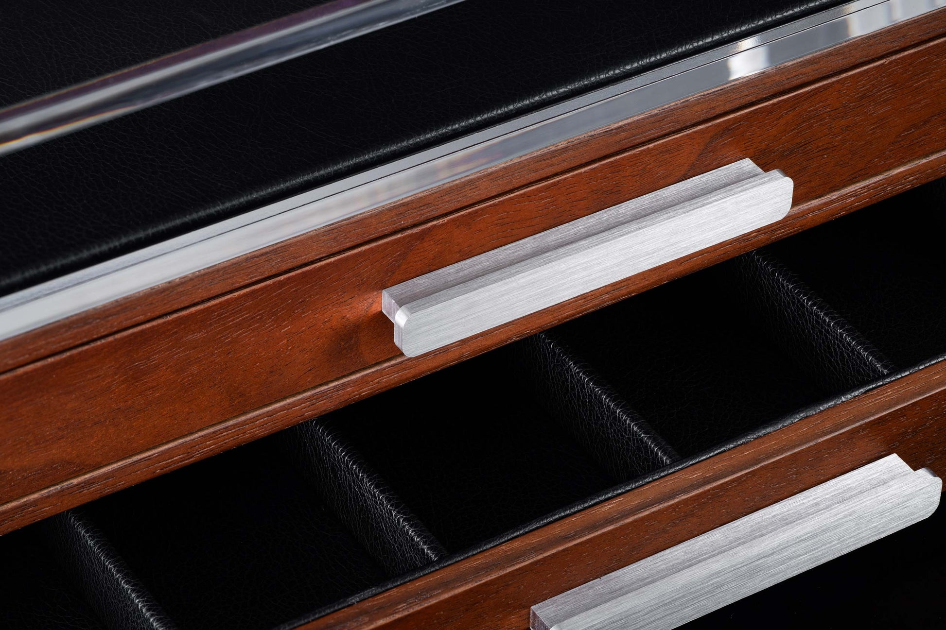 Collector's box of dark wood with black leather interior lining, silver trim, and brushed metal drawer pulls, angled close-up.