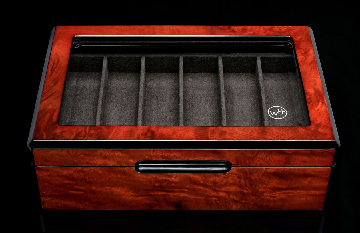 Reddish-brown burled wood collector display case with clear top, six grey velvet compartments, white logo, and a lower drawer with black handle.