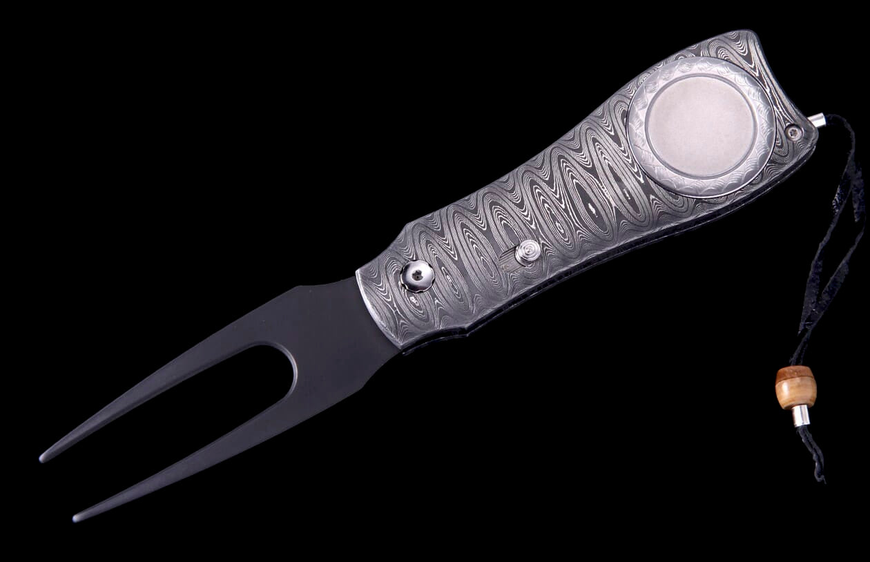 Damascus steel golf knife with a two-pronged end, round silver emblem, and wooden bead lanyard.